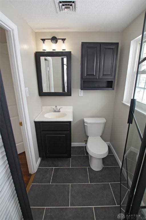 bathroom with toilet, vanity, tile patterned floors, and a textured ceiling