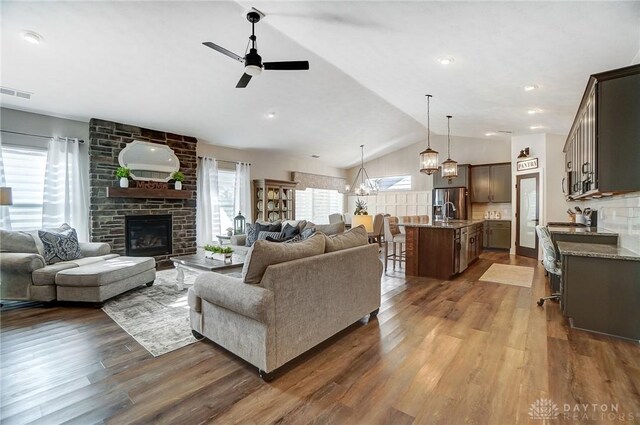 living room featuring lofted ceiling, ceiling fan, a brick fireplace, and hardwood / wood-style floors