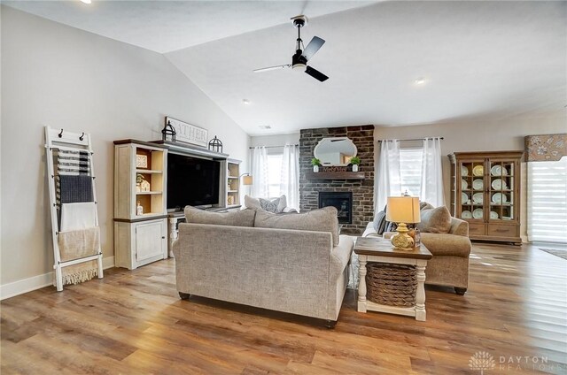 living room featuring ceiling fan, lofted ceiling, a fireplace, and wood-type flooring