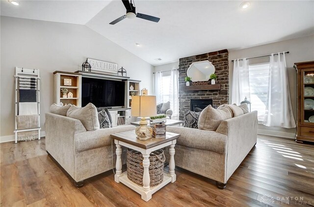 living room featuring vaulted ceiling, a fireplace, and light hardwood / wood-style floors