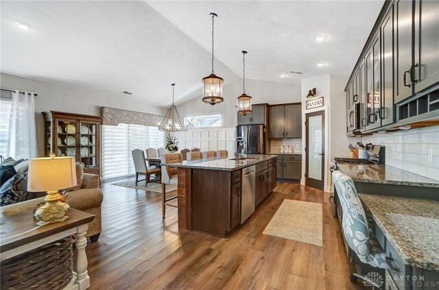 dining area featuring wood-type flooring, a chandelier, and vaulted ceiling