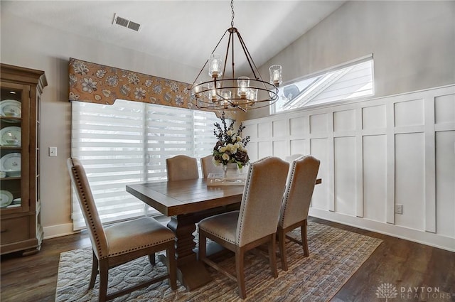 dining room with vaulted ceiling, dark hardwood / wood-style flooring, and an inviting chandelier