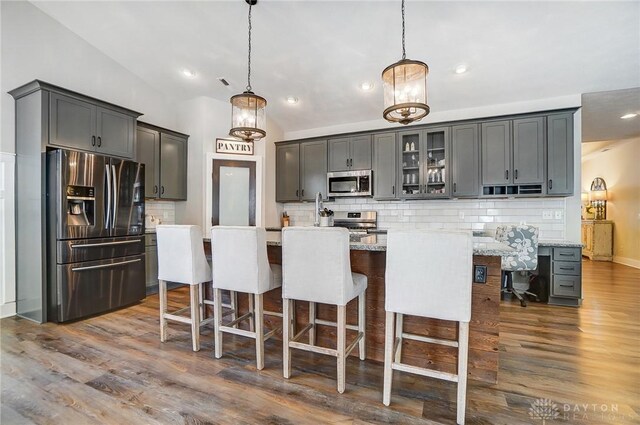 kitchen featuring light stone countertops, appliances with stainless steel finishes, hanging light fixtures, and sink