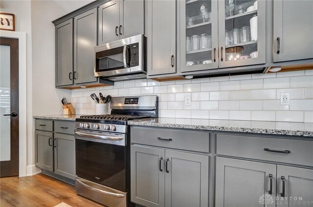 kitchen featuring appliances with stainless steel finishes, decorative light fixtures, sink, backsplash, and vaulted ceiling