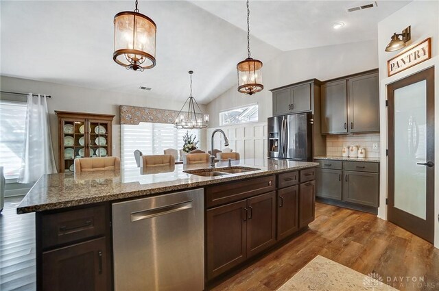 kitchen with hanging light fixtures, dark brown cabinets, dark stone counters, and a notable chandelier