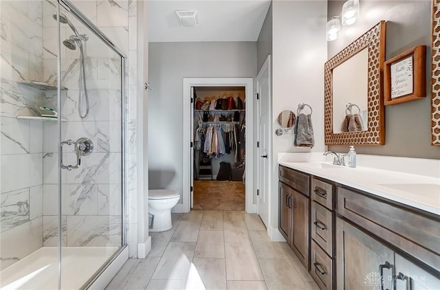 bathroom with toilet, a shower with shower door, and vanity