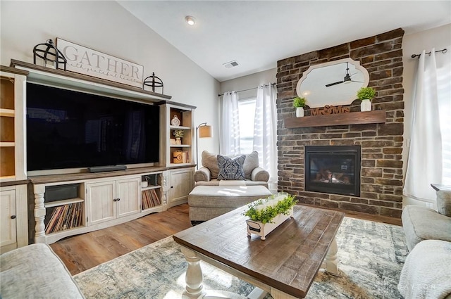 living room featuring lofted ceiling, light hardwood / wood-style floors, and a brick fireplace