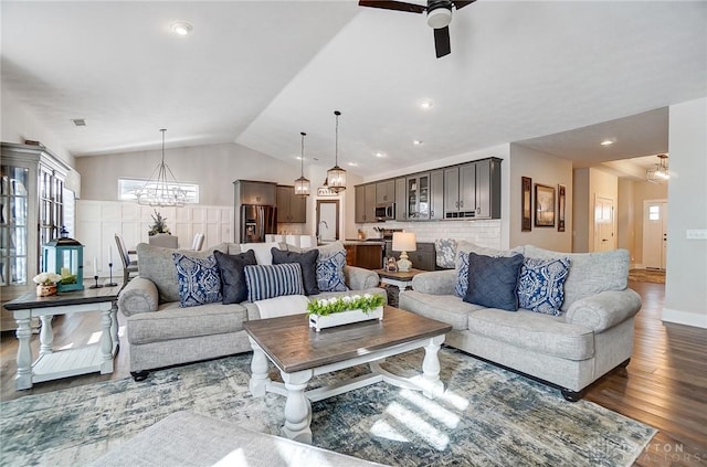 living room featuring dark hardwood / wood-style flooring, sink, ceiling fan with notable chandelier, and vaulted ceiling