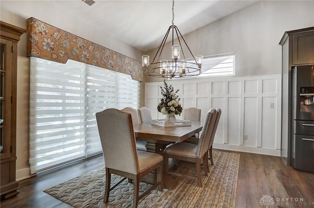 dining area with a notable chandelier, dark wood-type flooring, and vaulted ceiling