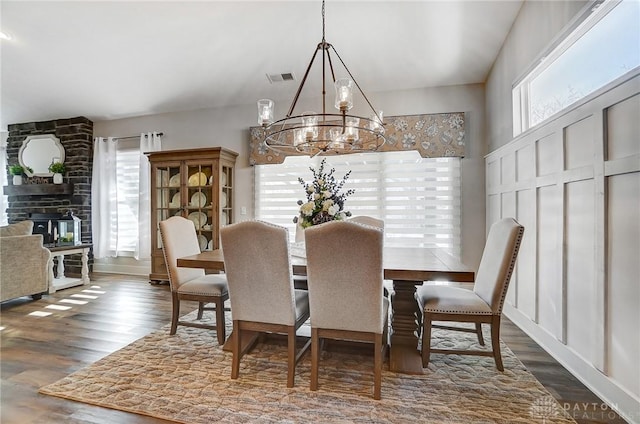 dining space with dark hardwood / wood-style flooring, a notable chandelier, and a large fireplace