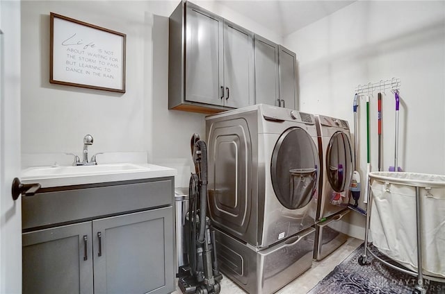 clothes washing area with cabinets, sink, and washer and clothes dryer