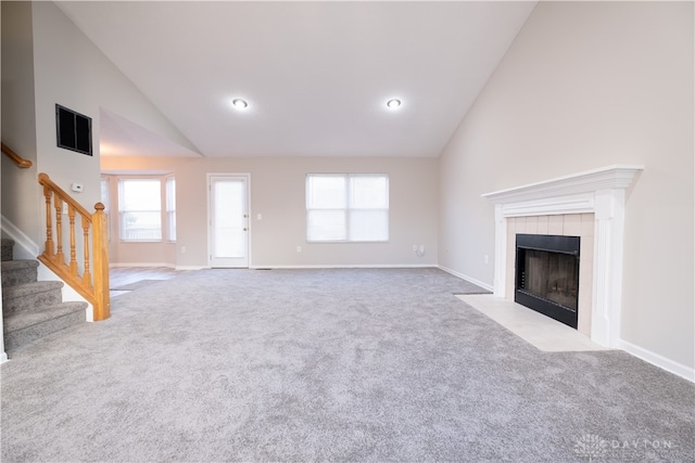 unfurnished living room featuring a fireplace, light colored carpet, and high vaulted ceiling