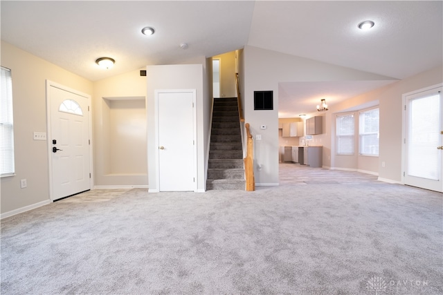 unfurnished living room featuring vaulted ceiling and light colored carpet