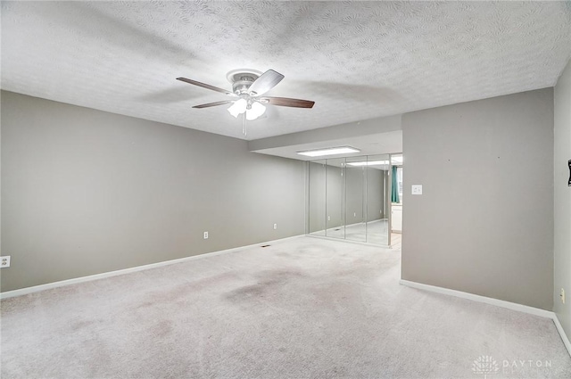 carpeted empty room with ceiling fan and a textured ceiling