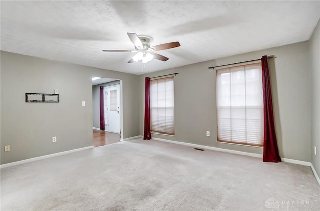 empty room featuring ceiling fan, light colored carpet, and a textured ceiling