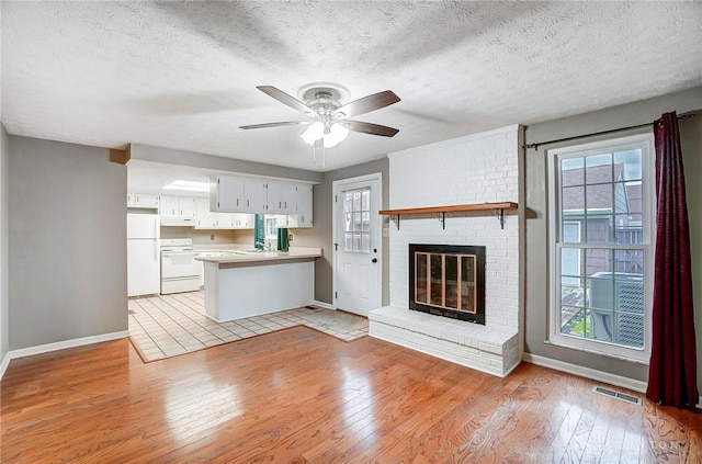 unfurnished living room with a textured ceiling, light hardwood / wood-style floors, and plenty of natural light