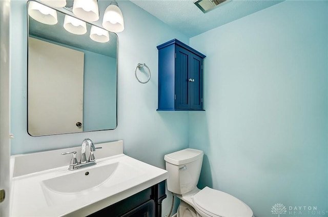 bathroom featuring toilet, a textured ceiling, and vanity