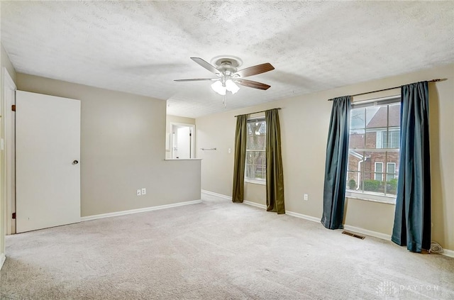 unfurnished room with ceiling fan, a textured ceiling, and light carpet