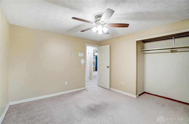 unfurnished bedroom featuring ceiling fan, light colored carpet, a closet, and a textured ceiling