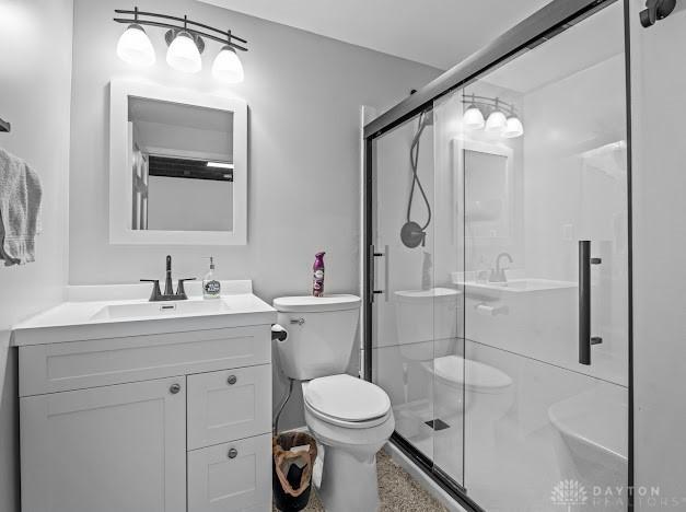 bathroom with an enclosed shower, vanity, and toilet