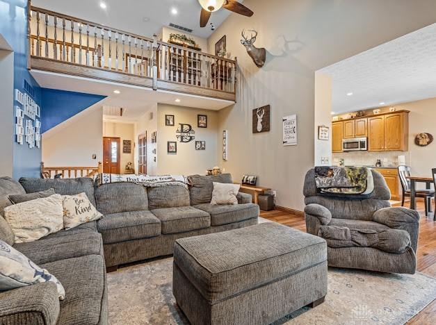 living room featuring ceiling fan, light hardwood / wood-style flooring, and high vaulted ceiling