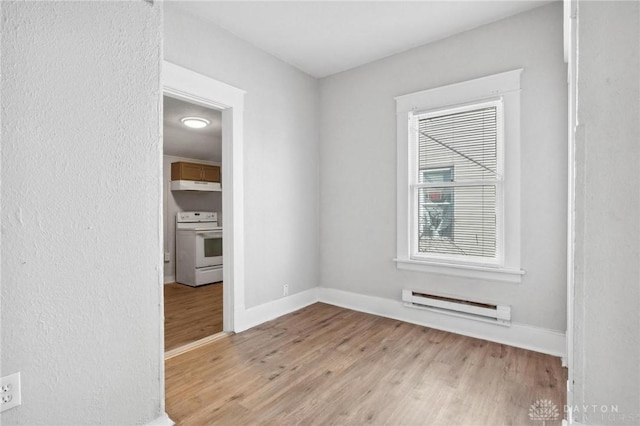 empty room with baseboard heating and light hardwood / wood-style flooring