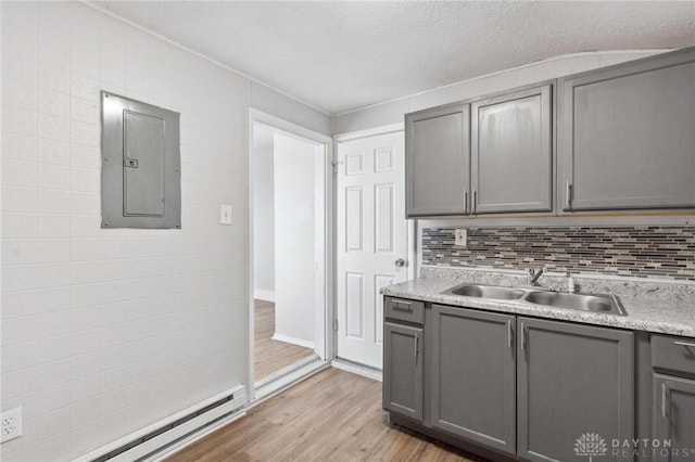 kitchen featuring electric panel, sink, light hardwood / wood-style flooring, gray cabinetry, and a baseboard radiator