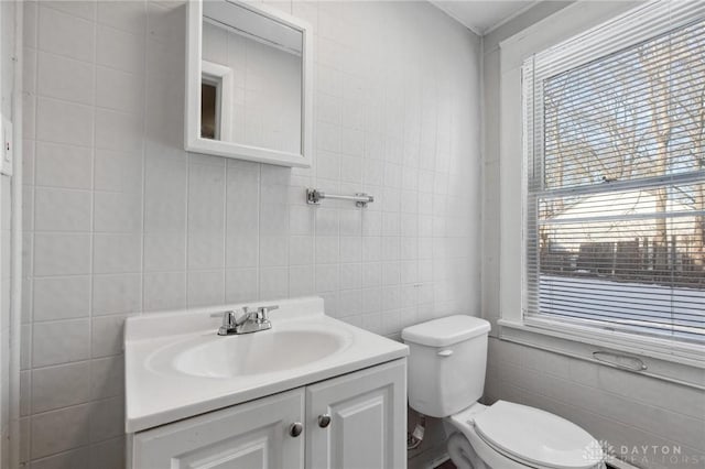 bathroom with toilet, vanity, and tile walls