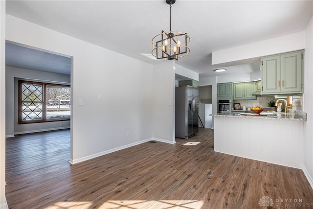 kitchen featuring backsplash, kitchen peninsula, green cabinetry, stainless steel appliances, and light stone counters