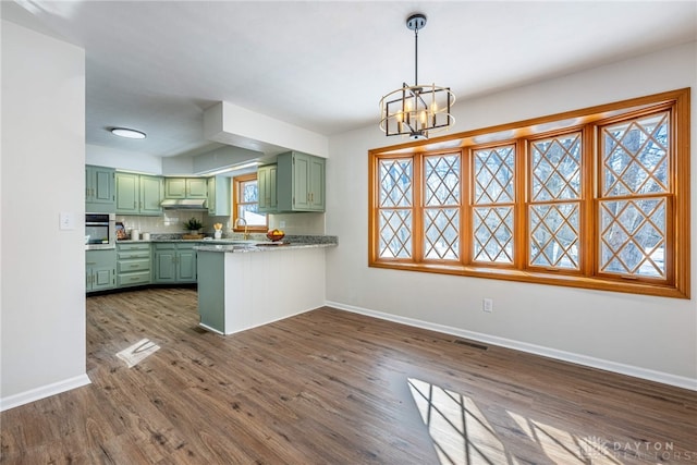 kitchen featuring kitchen peninsula, stainless steel oven, dark hardwood / wood-style floors, green cabinetry, and light stone counters