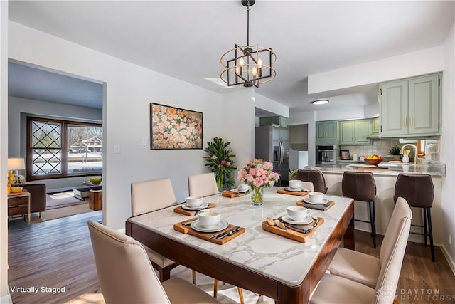 dining area with dark wood-type flooring, sink, and a chandelier