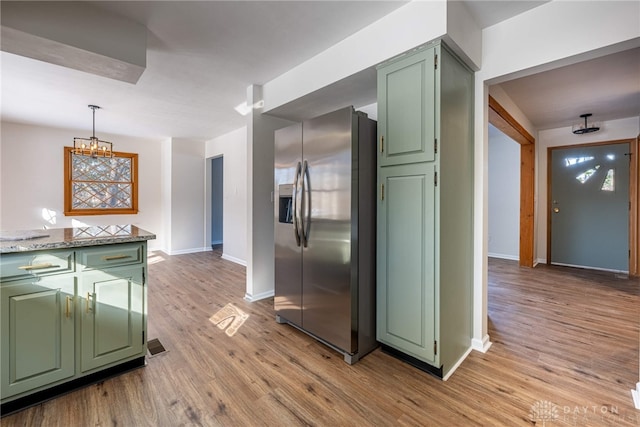 kitchen featuring stainless steel refrigerator with ice dispenser, light stone countertops, light hardwood / wood-style flooring, and green cabinetry