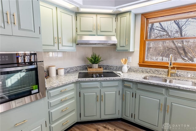 kitchen with sink, stainless steel oven, dark wood-type flooring, light stone counters, and black electric cooktop