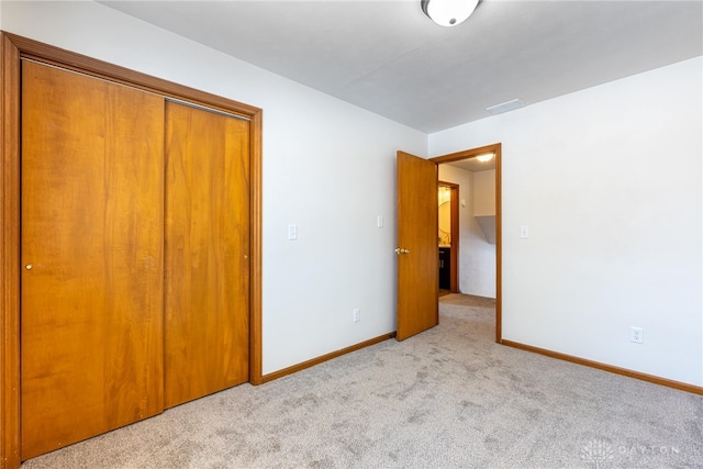 unfurnished bedroom featuring light colored carpet and a closet