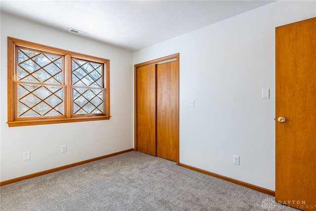 unfurnished bedroom featuring a closet and light colored carpet