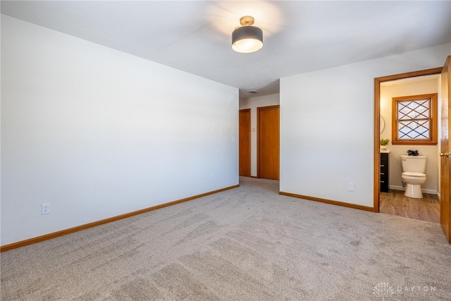 unfurnished bedroom featuring light carpet and ensuite bath