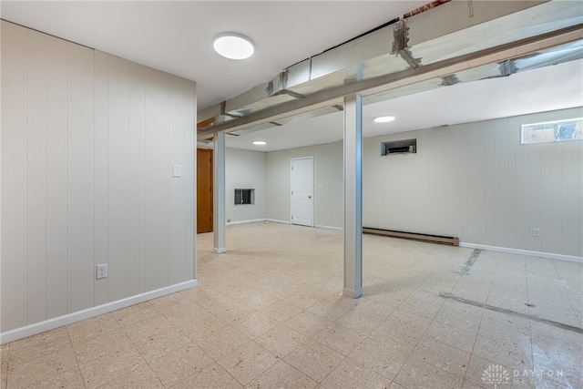 basement featuring baseboard heating and wooden walls