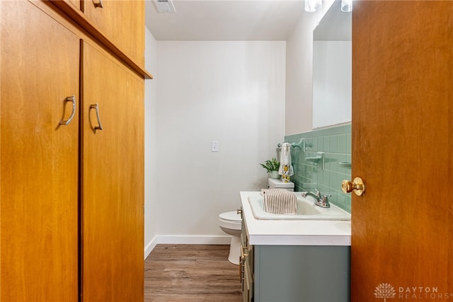 bathroom with toilet, decorative backsplash, hardwood / wood-style floors, and vanity