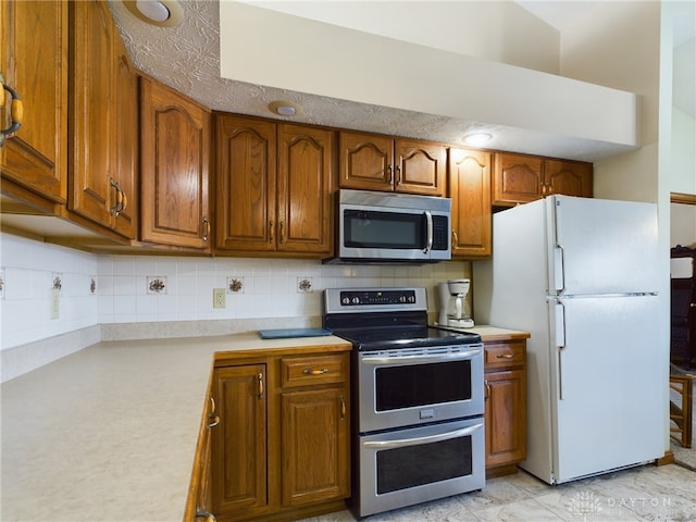 755 Willow Creek Way, Troy, OH 45373 - kitchen with appliances with stainless steel finishes, brown cabinetry, light countertops, and tasteful backsplash