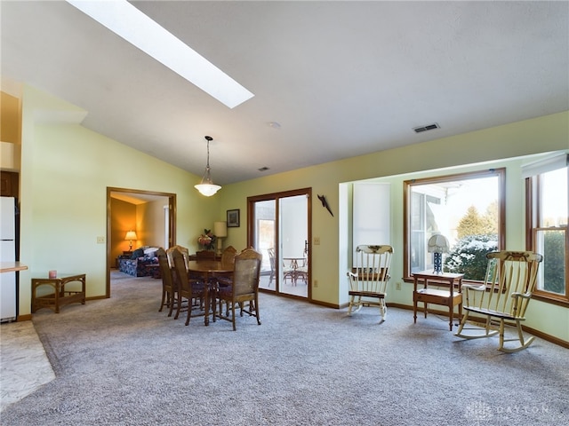 carpeted dining space with a wealth of natural light and lofted ceiling with skylight