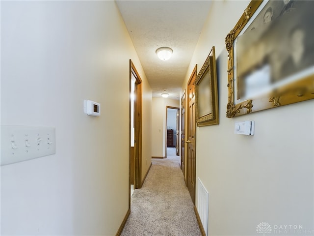 corridor with light carpet, a textured ceiling, and a mail area