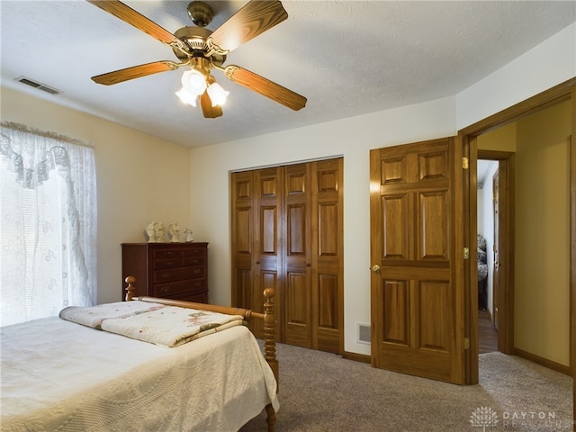 carpeted bedroom featuring ceiling fan, a textured ceiling, and a closet