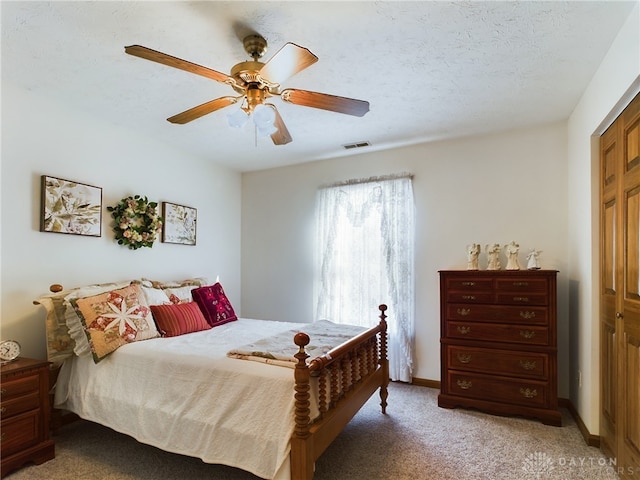 carpeted bedroom with ceiling fan, a closet, and a textured ceiling