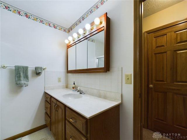 bathroom with a textured ceiling, backsplash, and vanity