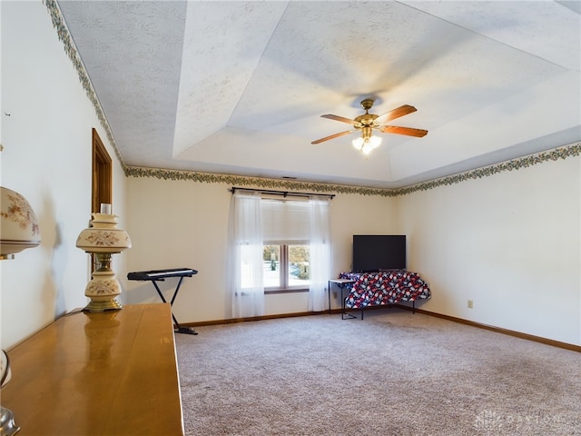 unfurnished room with a textured ceiling, ceiling fan, carpet floors, and a tray ceiling