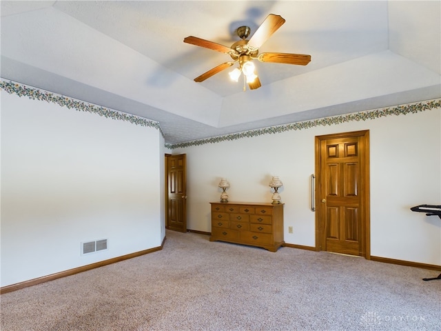 unfurnished bedroom featuring ceiling fan, light colored carpet, and a tray ceiling