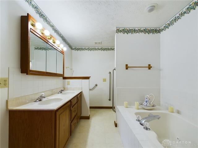 bathroom featuring a relaxing tiled tub, a textured ceiling, and vanity