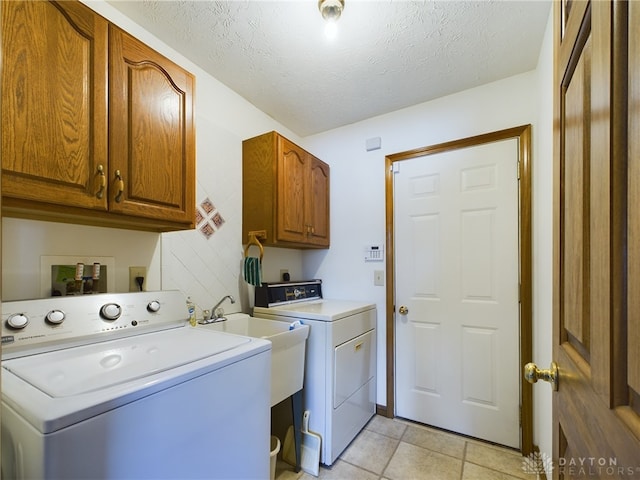 washroom featuring washer and dryer, cabinets, a textured ceiling, and light tile patterned floors