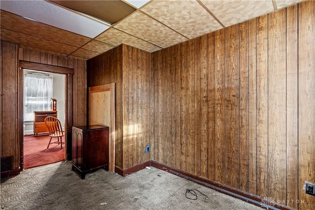 spare room with carpet and wooden walls