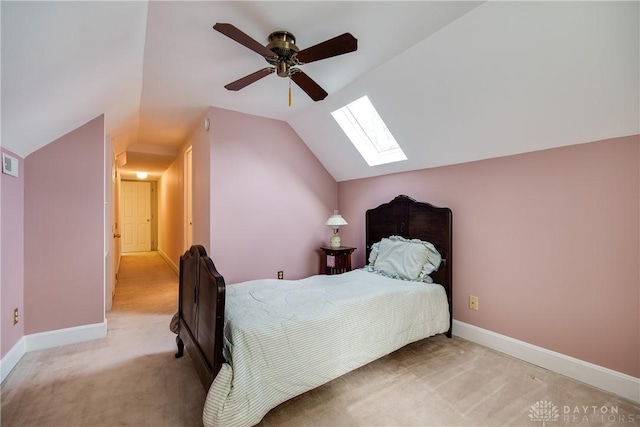 carpeted bedroom with ceiling fan and vaulted ceiling with skylight